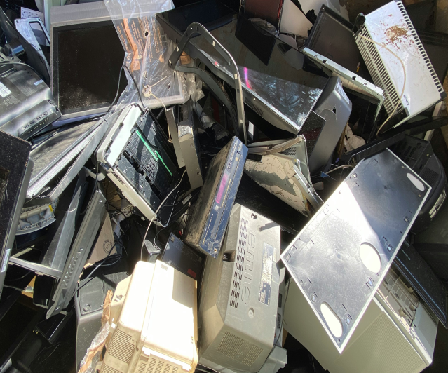 Pile of discarded electronic waste, including old computers, monitors, and devices.