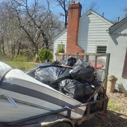 Trailer loaded with black garbage bags and old mattresses for junk removal by big blue junk removal.